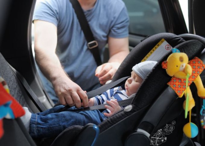 Mężczyzna montuje bezpieczny fotelik z dzieckiem w samochodzie